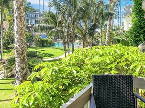 A lush garden with palm trees and a pool in the background.