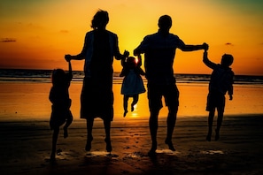 En siluett av en familj mot en solnedgång på en strand.
