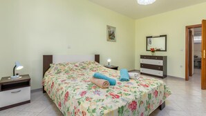 Ein Schlafzimmer mit floralem Bettbezug, zwei Nachttischlampen, einem Schminktisch und einem Bild an der Wand.