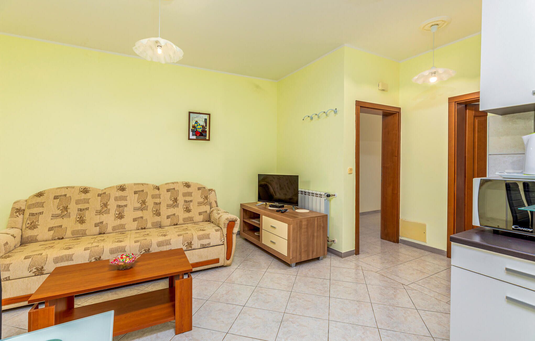 Una sala de estar con un sofá, una mesa de centro, un televisor y un mueble bajo.