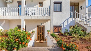 Ein zweistöckiges Gebäude mit Balkon, einer Tür und einer Treppe, die zum oberen Stock führt.
