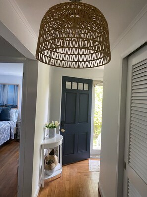 Stunning hallway with a console table, vase, and woven basket, leading to a dark blue door.