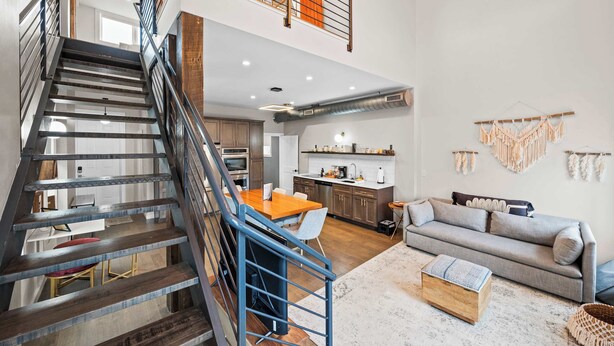 A spacious loft with a central staircase, a kitchen, a dining area, and a living room. - 4 Apartments, Downtown, Walk to Cincy Stadiums! (Covington)