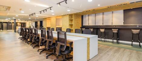 Una sala de conferencias moderna con una larga mesa, sillas de oficina negras y una pared de acento blanca.