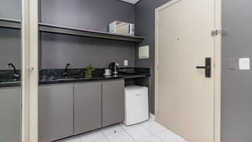 Una cocina moderna con armarios grises, un refrigerador blanco y un microondas sobre una repisa.
