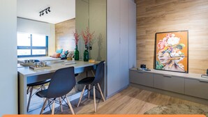 A modern kitchen with a wooden countertop, two black chairs, and a large painting on the wall. - Century Park by My Way (Porto Alegre)