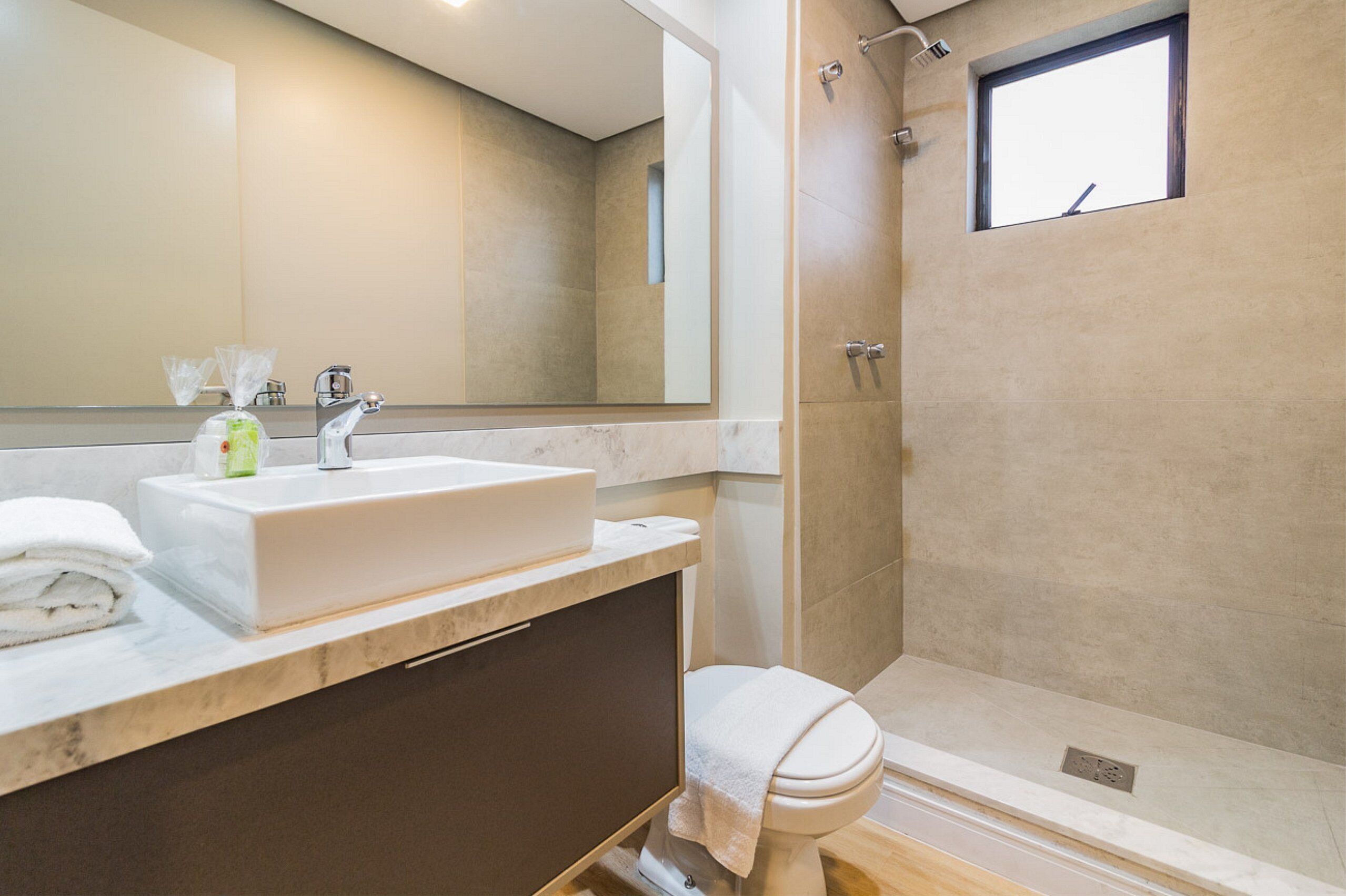 Une salle de bain moderne avec un grand miroir, un lavabo et une douche.