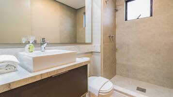 Une salle de bain moderne avec un grand miroir, un lavabo et une douche.
