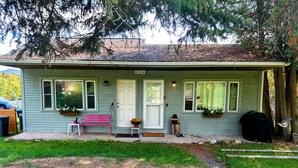 A single-story house with a front porch, a bench, and a welcome sign. - Yinzer House - Hike and Ski (Jay)
