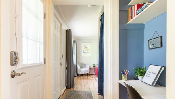 A hallway leading to a room with a desk, bookshelf, and a framed picture on the wall. - Yinzer House - Hike and Ski (Jay)