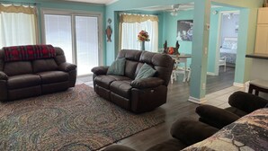 A living room with two leather sofas, a patterned rug, and a ceiling fan. - Mid lake, pet friendly 4 bedroom, 3 bath with protected swim area (Dadeville)