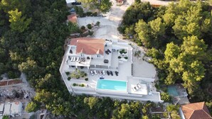 An aerial view of a modern villa with a swimming pool, multiple lounge areas, and a large garden. - Holiday Hvar LUX 2.  (Vrbanj)