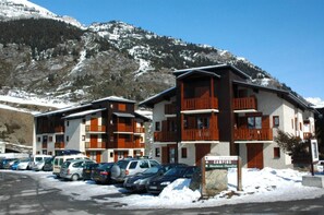 Ein mehrstöckiges Hotel mit Balkonen, einem Parkplatz und einem Schild, das auf einen Campingplatz hinweist.