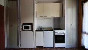 A compact kitchen with white cabinets, a microwave, a small refrigerator, a sink, and a stove. - Ground floor, tv, ski locker, 23m², Val Cenis (Lanslevillard)