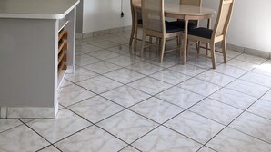 Un espace repas comprenant une table et des chaises, un ventilateur de plafond, un téléviseur fixé au mur et une porte.