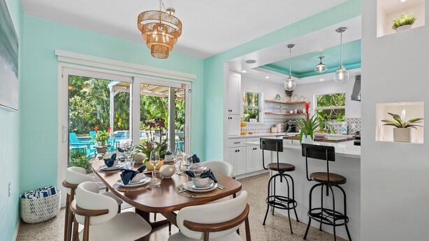 Una cocina moderna con armarios blancos, una isla central y taburetes de bar.