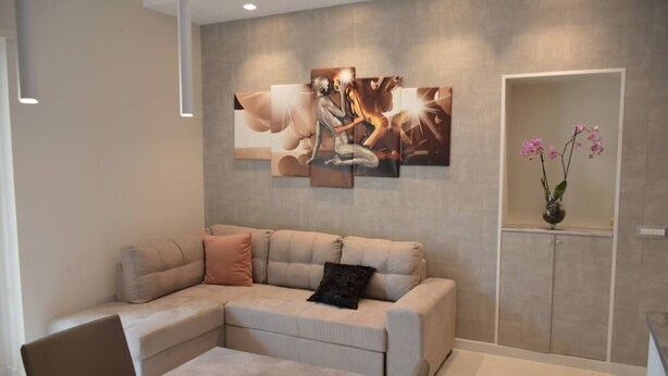 Ein modernes Wohnzimmer mit einer Eckcouch, einem Couchtisch und einem an der Wand befestigten Kunstwerk.