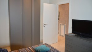 Ein Schlafzimmer mit einem Bett, einem Fernseher auf einer Kommode und einem Schiebetürenschrank.
