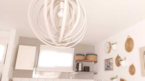 Una cocina moderna con armarios blancos, una isla central y una lámpara colgante.
