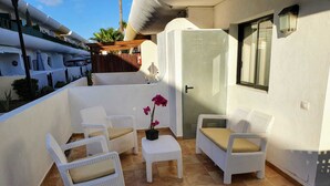 Un pequeño patio con mobiliario de mimbre y una orquídea en maceta.