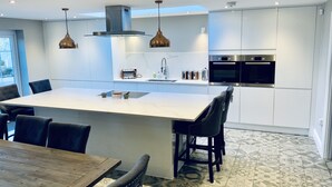A modern kitchen with a central island, stainless steel appliances, pendant lighting, and patterned flooring.