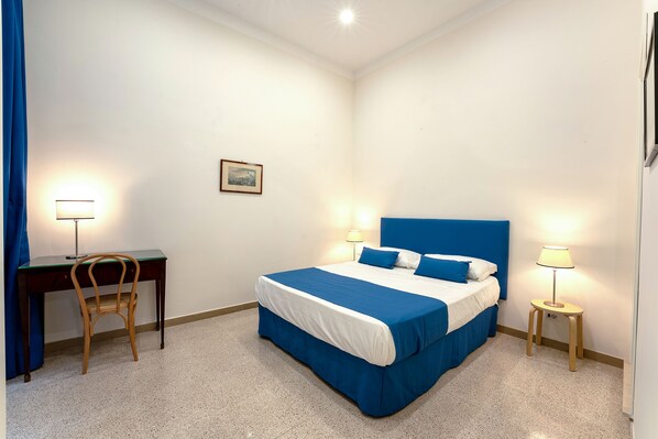 A bedroom with a bed, two bedside tables with lamps, a desk with a chair, and a picture on the wall. - ARBITER TOLEDO – 4 APARTMENTS (Napoli)