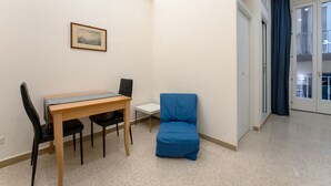 A room with a wooden table, two black chairs, a blue chair, a small white table, and a framed picture on the wall. - arbiter toledo - 2 apartments (Napoli)