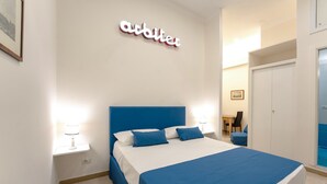 A bedroom with a bed, a nightstand, a wall-mounted sign, a door, and a window. - arbiter toledo - 2 apartments (Napoli)
