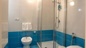A bathroom with a glass-enclosed shower, a white pedestal sink, and a toilet. - arbiter toledo - 2 apartments (Napoli)