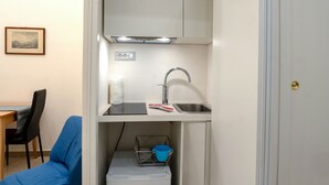 A compact kitchenette with a sink, a small refrigerator, and a blue chair. - arbiter toledo - 2 apartments (Napoli)