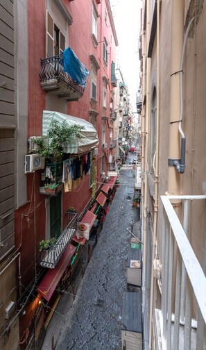 A narrow street with buildings on either side, some with balconies and outdoor seating areas. - arbiter toledo - 2 apartments (Napoli)