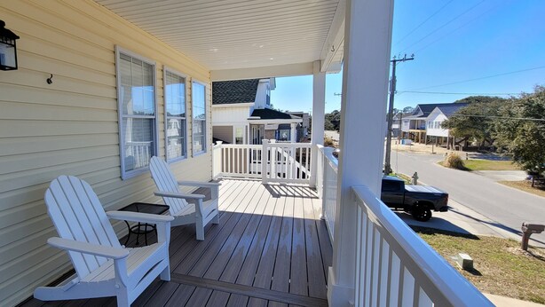 A wooden porch with white Adirondack chairs and a white railing. - Pet Friendly Home with Private Tiki Bar - 3-minute drive to the beach! (Kill Devil Hills)