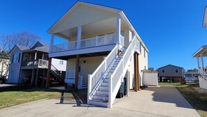 A two-story house with a front porch and a staircase leading to the upper floor. - Pet Friendly Home with Private Tiki Bar - 3-minute drive to the beach! (Kill Devil Hills)