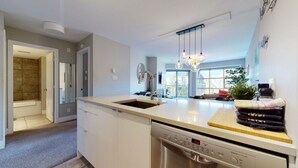 Una cocina moderna con lavavajillas, un fregadero y una encimera con tabla de cortar y toallas.