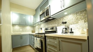 A modern kitchen with grey cabinets, a stainless steel oven, a microwave, and a coffee maker.
