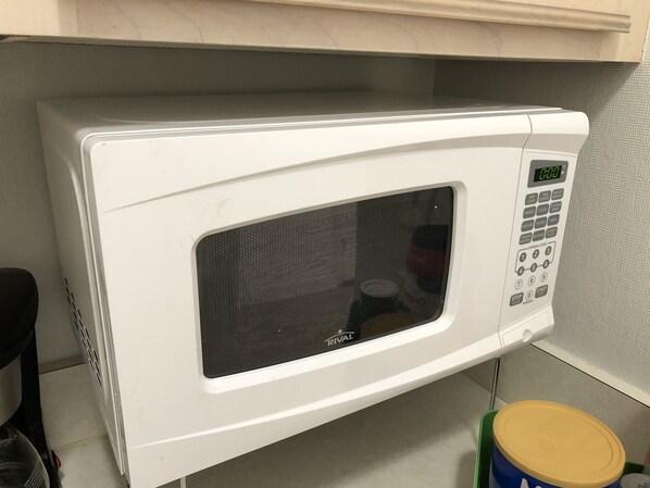 Un horno microondas blanco con pantalla digital y panel de control, sobre una encimera de cocina.