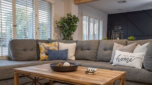 Una sala de estar moderna con un sofá seccional gris, una mesa de centro de madera y cojines decorativos.