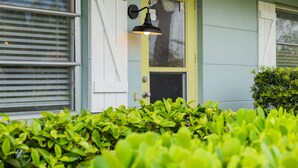 A house with a yellow door, a black mailbox, and a green bush in the foreground.
