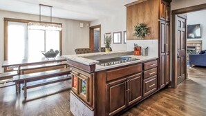 Une cuisine spacieuse avec un grand îlot central, des armoires en bois et un lustre.