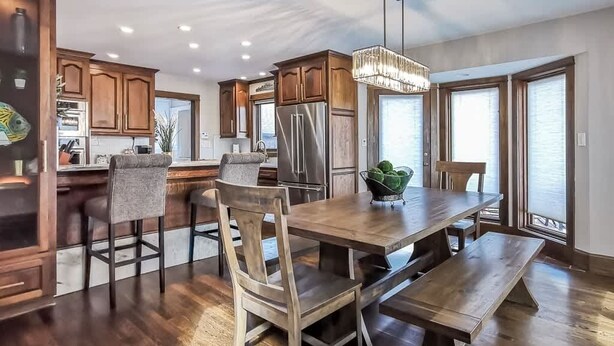 Une cuisine spacieuse avec des meubles en bois, un grand îlot central et un coin repas équipé d’une banquette.