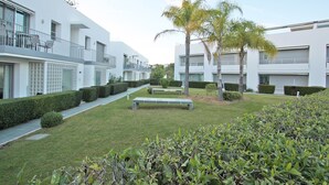 A modern residential building with a well-maintained lawn, benches, and palm trees. - Believe in Dream, Apart. Contemporâneo com Piscina (Tavira - Santa Maria)