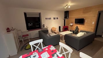 Ein gemütliches Wohnzimmer mit zwei grauen Sofas, einem kleinen weißen Tisch und einer roten Tischdecke mit verschiedenen Karten.