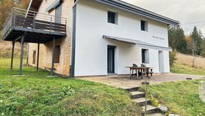Une maison moderne à deux étages, dotée d’un balcon, d’un espace extérieur aménagé et couvert, et d’une enseigne indiquant « Gîtes de la Chaouette ».