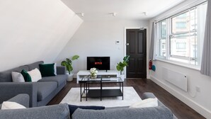 A modern living room with a grey sofa, a coffee table, and a TV displaying 'NETFLIX'. - home.ly London Liverpool Str Apartments (London)