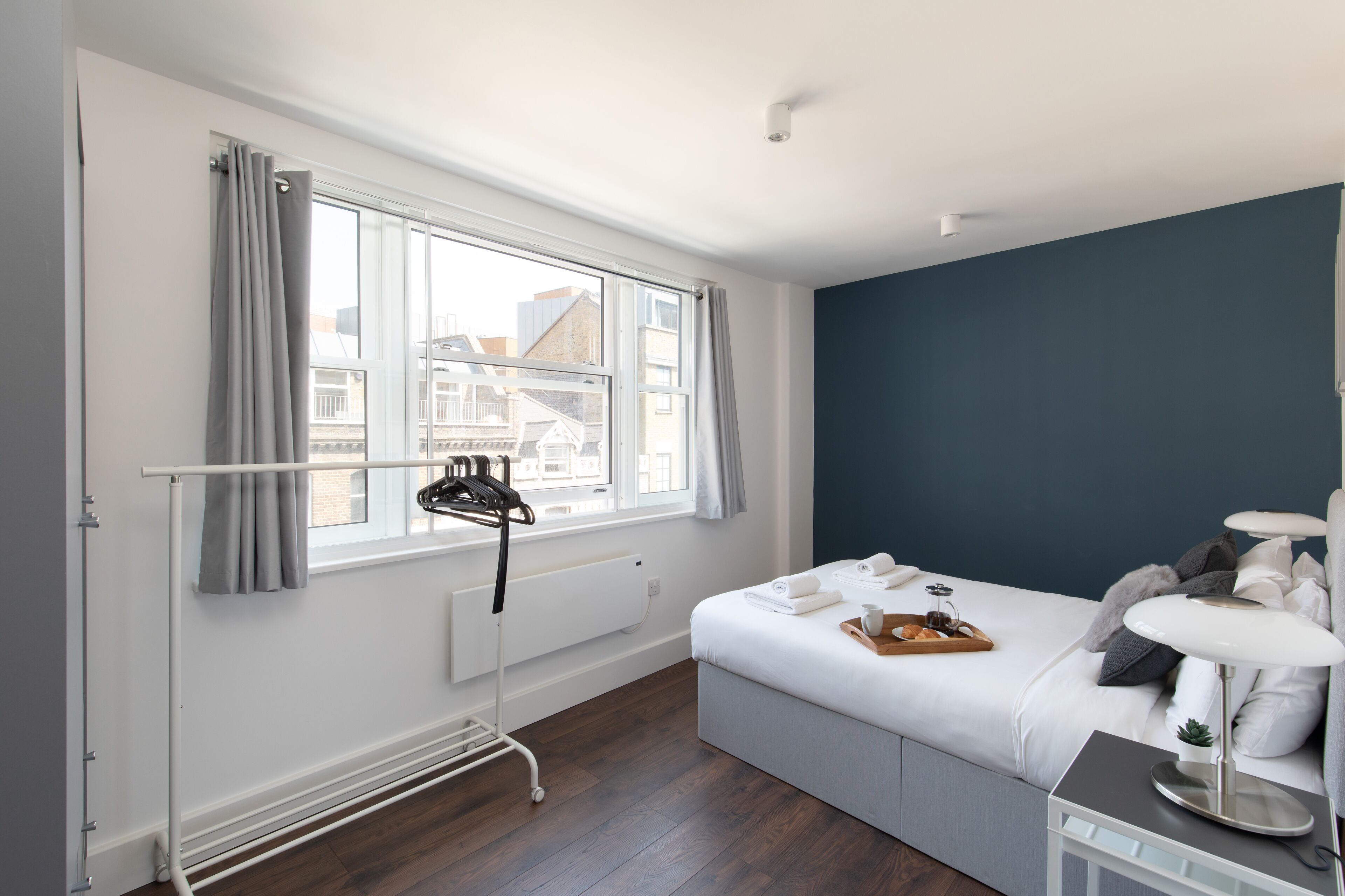 Un dormitorio moderno con cama, mesita de noche y ventana con cortinas.