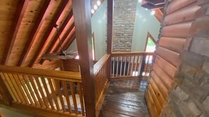 A wooden staircase with a stone wall on one side and a wooden railing on the other.