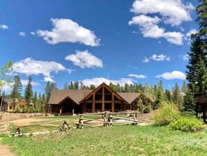 Stunning lodge with a central bay window and steeply pitched roof, set amidst a beautifully manicured lawn.