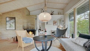 A cozy living room with a fireplace, a round table with wine glasses, a comfortable chair, and a sofa.