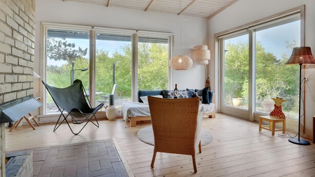 A spacious room with large windows, a brick wall, and a mix of modern and rustic furniture.