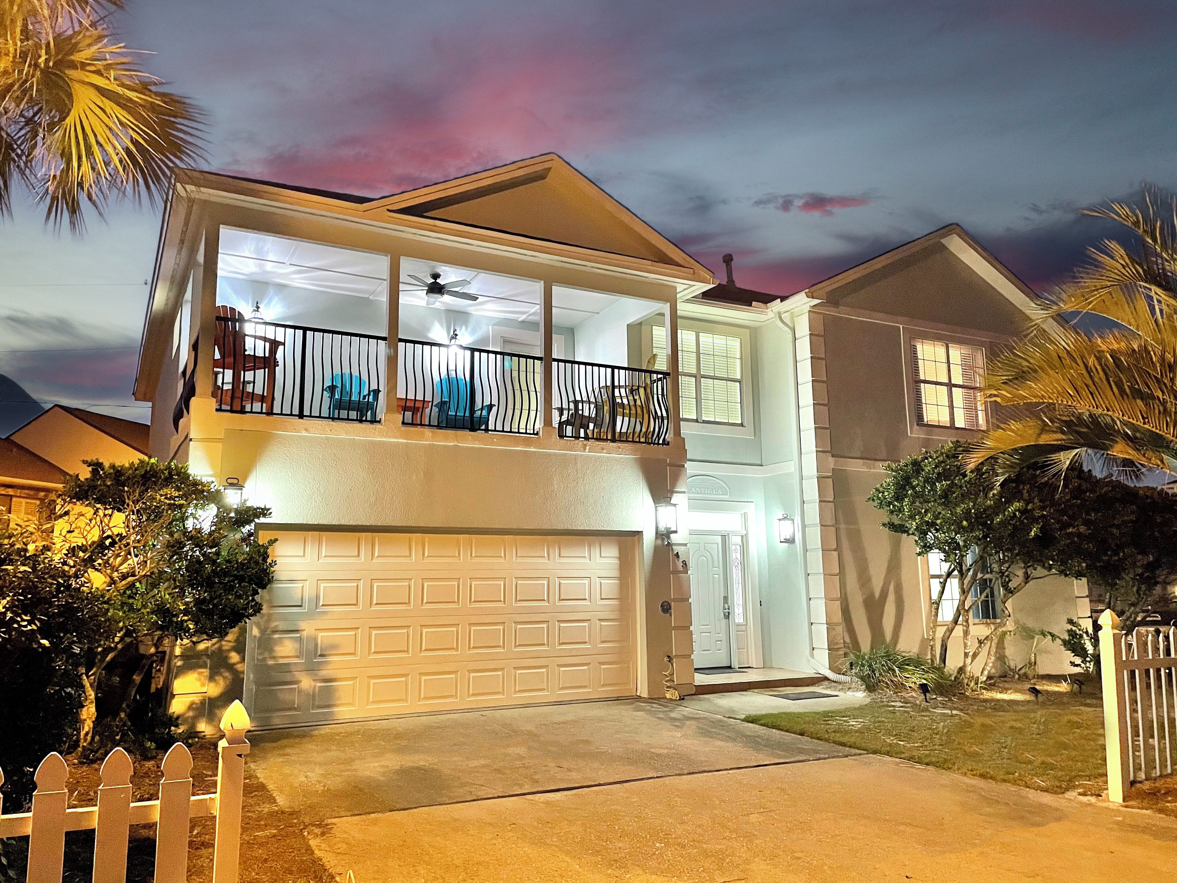A two-story house with a garage, a balcony with a railing, and a well-lit entrance.